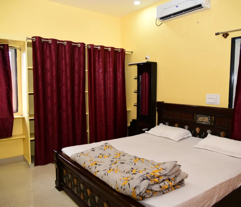 This image displays an air-conditioned deluxe room at Vasavi Homestay in Mantralayam, Kurnool.